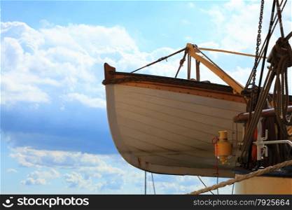 Old wooden lifeboat on a ship blue sky background