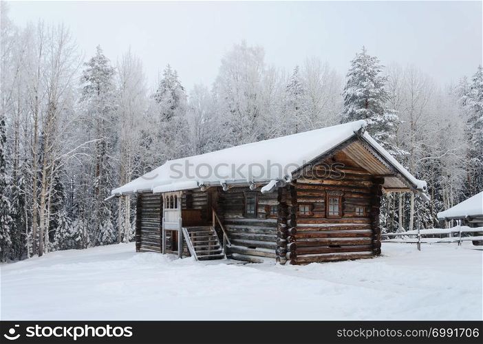 Old wooden peasant house covered with snow in the northern open air museum Malye Korely near Arkhanglesk, Russia. Winter frosty day.
