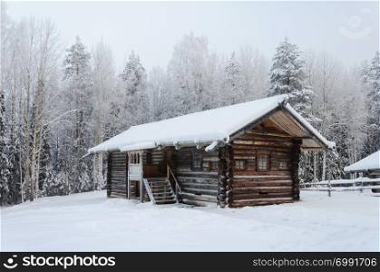 Old wooden peasant house covered with snow in the northern open air museum Malye Korely near Arkhanglesk, Russia. Winter frosty day.