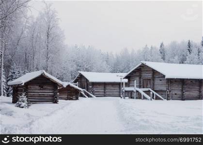 Old wooden peasant houses with barns in the northern open air museum Malye Korely near Arkhanglesk, Russia. Winter frosty day.