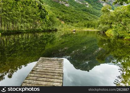 Old wooden pier on lake pond in summer, peaceful norwegian landscape. Old wooden pier on lake pond in summer