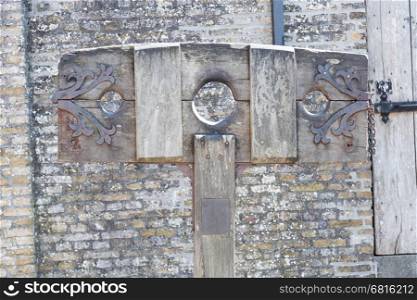 Old wooden pillory close up on castle stone wall background
