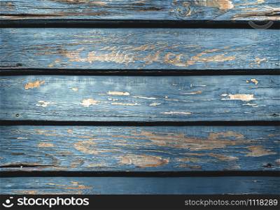 Old wooden planks background with shriveled blue paint. Blue wood backdrop. Rustic aged wooden table close-up. Wood texture and weathered paint.