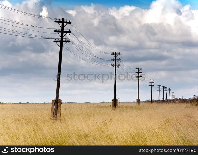 Old wooden poles - the line of electricity transmissions - in the field