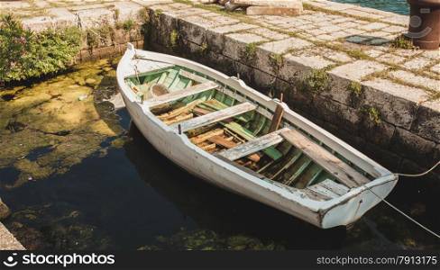 Old wooden rowboat mooring to ancient stone berth