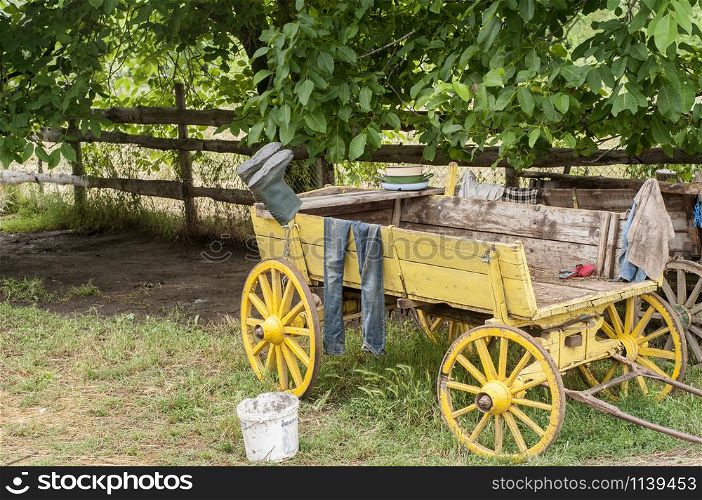 Old wooden rural cart in country village farm yard with boots and clothing on it