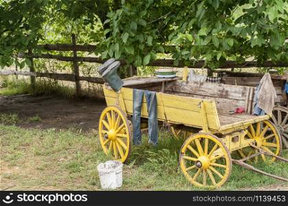 Old wooden rural cart in country village farm yard with boots and clothing on it