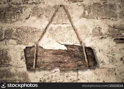 Old wooden sign hanging on a stone wall