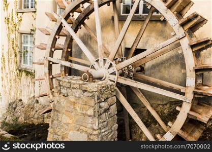 old wooden water mill on stone wall