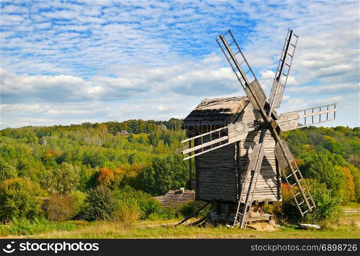 old wooden windmill in field and sky