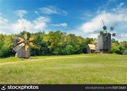 old wooden windmills in a field and sky