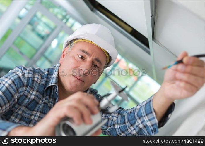 old worker in white helmet repairing