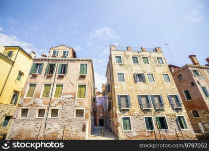 Old worn buildings in Italy in the summer with many windows and laundy hanging in the street