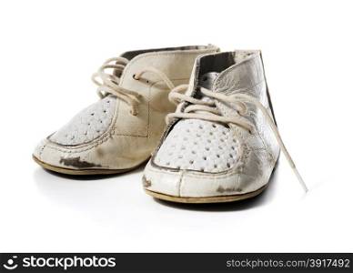 Old worn vintage leather white baby shoes isolated on white with natural shadows.