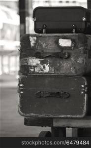 Old worn vintage suitcases stacked on train railway platform in . Old vintage suitcases stacked on train railway platform in sepia finish