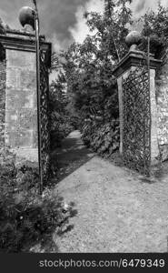 Old wrought iron full size garden gate and brick wall in black a. Beautiful old wrought iron full size garden gate and brick wall in black and white