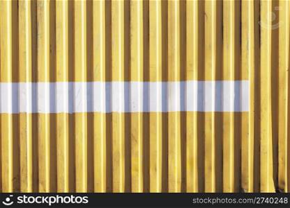 Old yellow metallic cargo container with a white stripe.