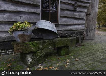 old zinc tub with old agricultural tools in a yard on a bench made of stones overgrown with moss
