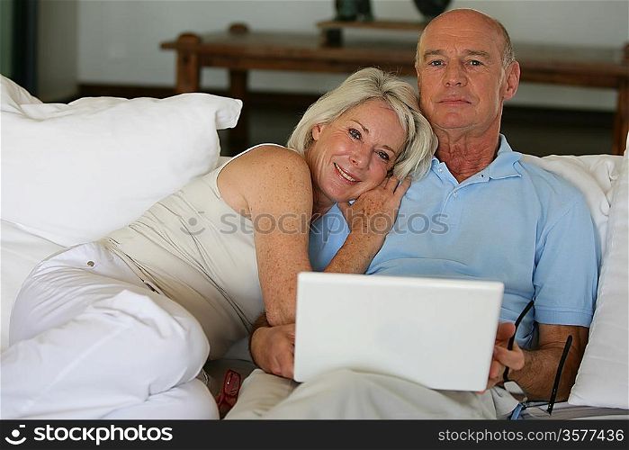 Older couple sitting on a sofa with a laptop