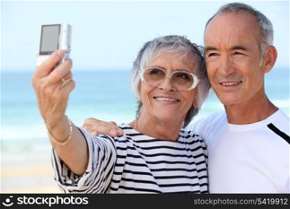 Older couple taking their own photograph at the beach