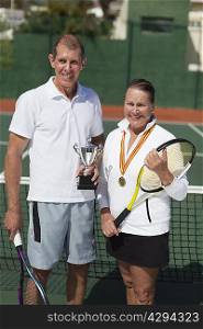 Older couple with trophy on tennis court