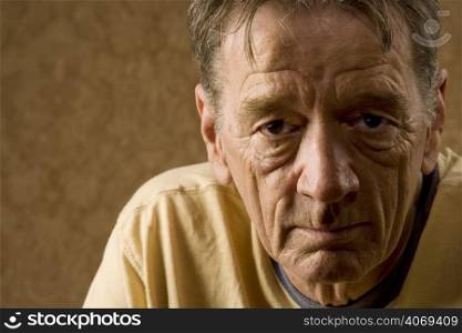 Older depressed man in front of wallpaper