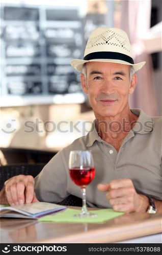 Older gentleman tourist drinking a glass of rose in a restaurant