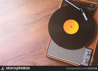 Older Gramophone with a vinyl record on wooden table, top view and copy space,photo.