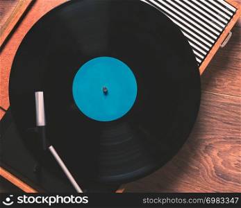 Older Gramophone with a vinyl record on wooden table, top view close up,vintage style.