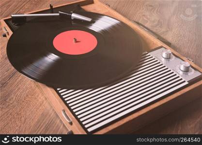 Older Gramophone with a vinyl record on wooden table,vintage style.