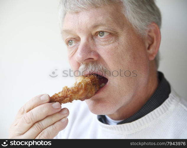 older man biting into fried chicken