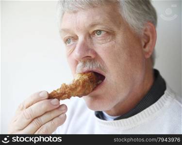 older man biting into fried chicken