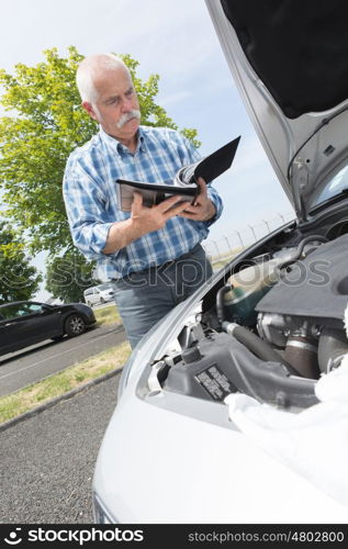 older man checking levels and servicing his car