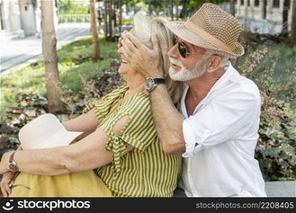 older man covering woman s eyes with her palms