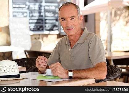 Older man drinking an expresso outside a cafe
