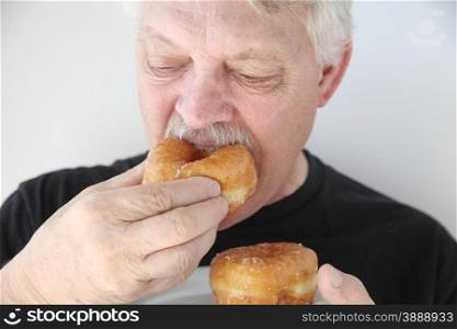 Older man enjoys a bakery yeast doughnut.