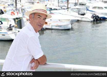 Older man in a straw panama hat standing by a marina