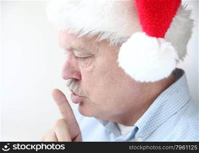 older man makes a shushing gesture with his index finger