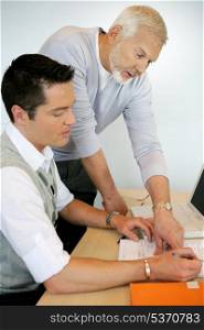 Older man pointing out something in a document to a colleague