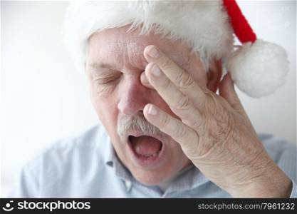 older man rubs his eye and yawns