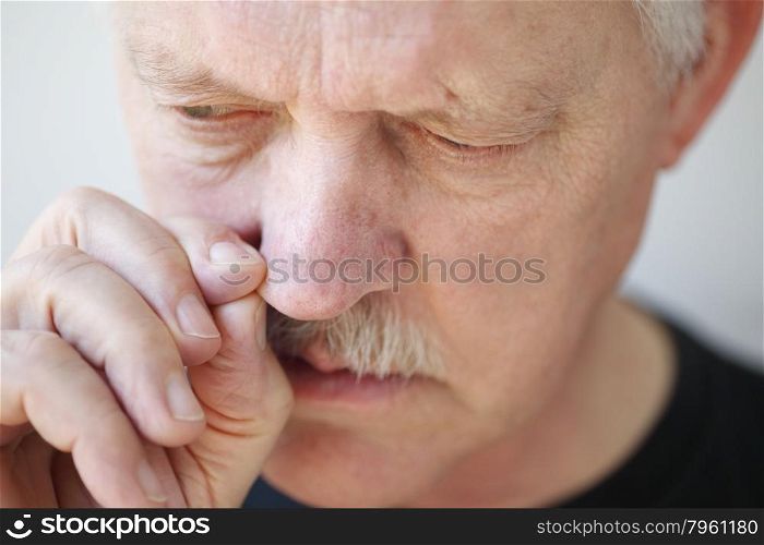 Older man tries to relieve his stopped up nostril.