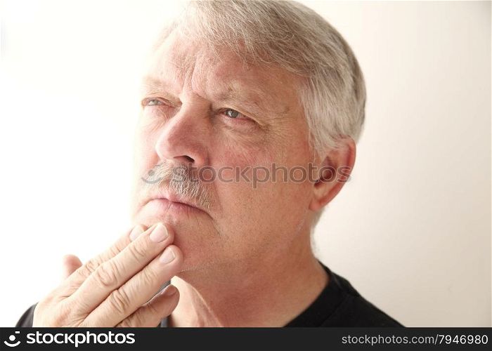older man with fingers on chin and pensive expression