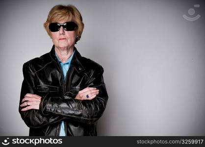 Older senior woman in a black leather jacket and sunglasses.