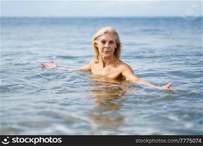 Older woman in good shape bathing in the sea. Elderly female enjoying her retirement at a seaside retreat.. Mature woman in good shape bathing in the sea.