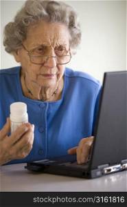 Older woman on laptop holding medication