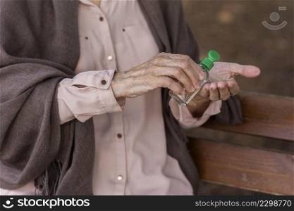 older woman using hands sanitizer