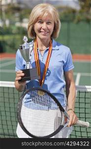 Older woman with trophy on tennis court