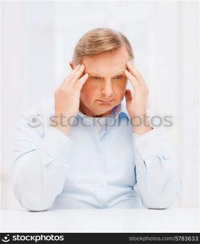 oldness, business and people concept - stressed old man holding head at home