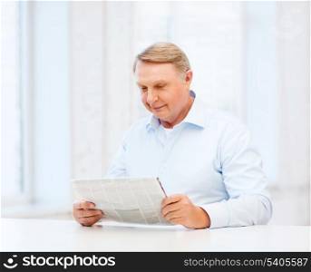 oldness, news, leisure and happiness concept - old man at home reading newspaper