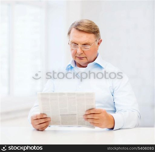 oldness, news, leisure and happiness concept - old man at home reading newspaper